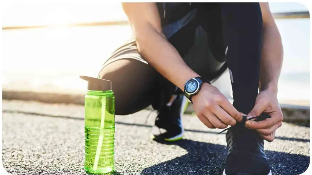 a person tying their shoe with a water bottle. (No gender, age, or ethnicity information present in the description.)